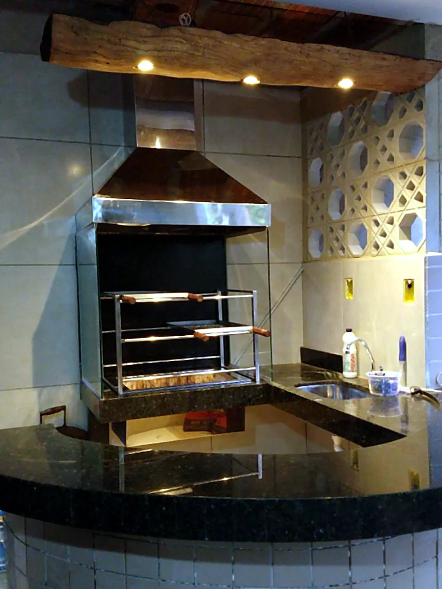 Churrasqueira em aço inox em área gourmet com acabamento em granito