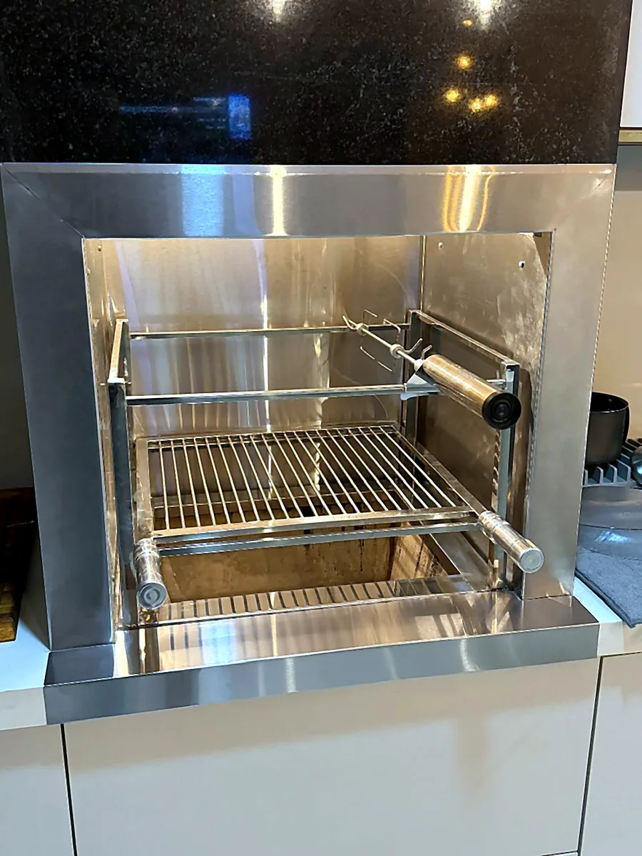 Churrasqueira em inox instalada sobre bancada em cozinha planejada