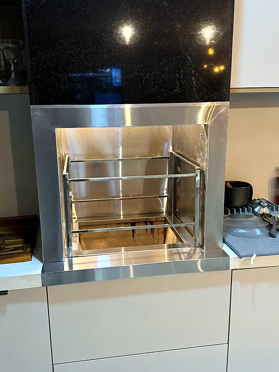 Churrasqueira de inox integrada a cozinha planejada com bancada escura