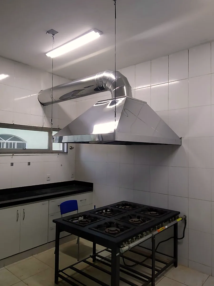 Coifa em aço inox sobre fogão industrial em cozinha comercial