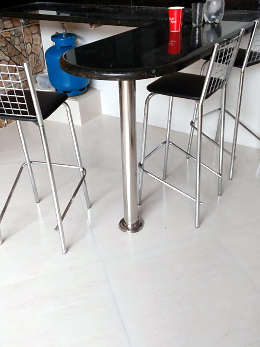 Mesa alta com base em inox e banquetas
